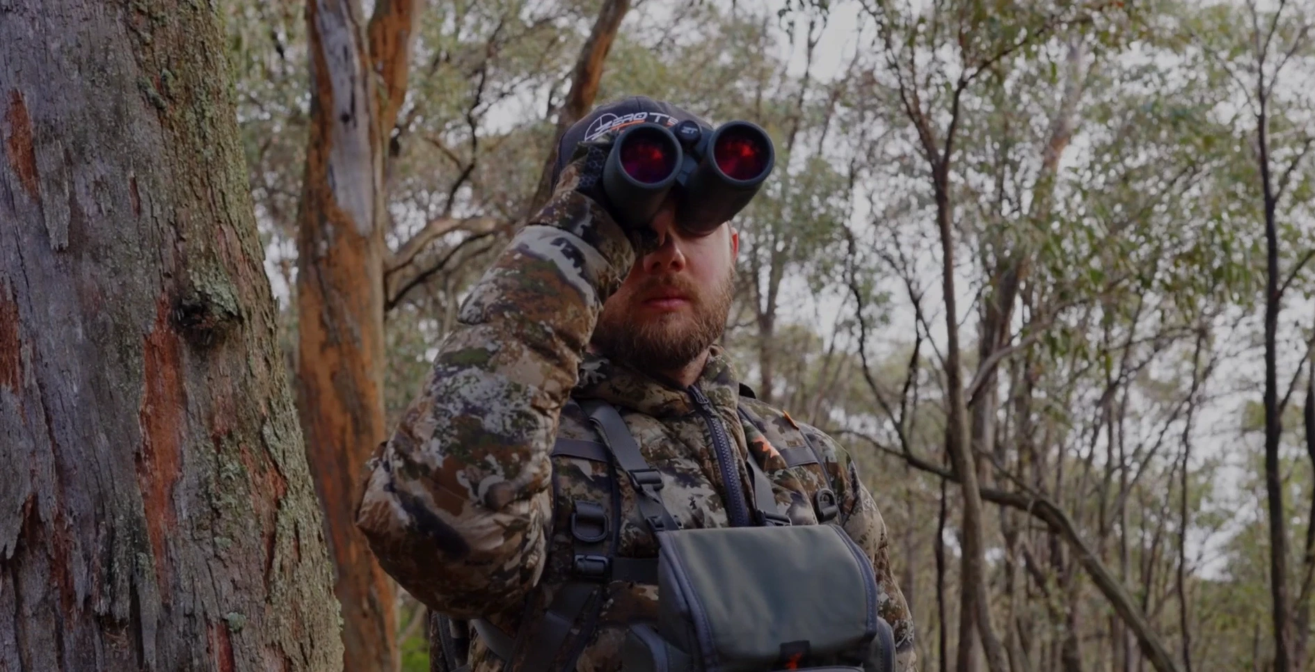 Cazador observando con binoculares ZeroTech en el monte australiano.